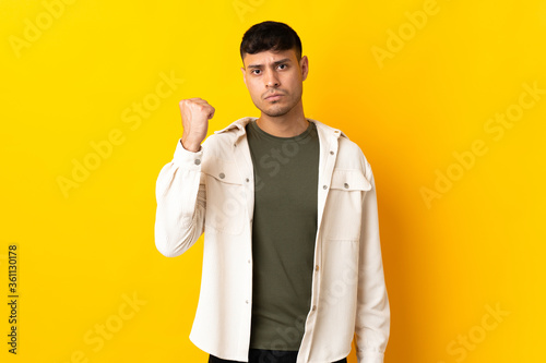 Young Colombian man isolated on yellow background with unhappy expression