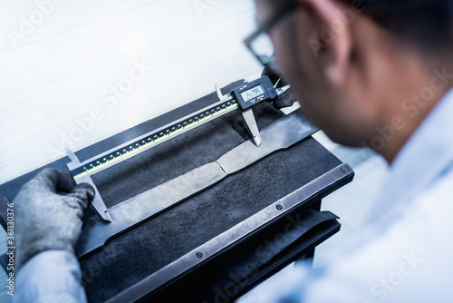 Tensile Testing, Engineer using digital vernier to measure the elongation period of the material specimen in the industrial factory laboratory. Mechanical properties of a material test. photo