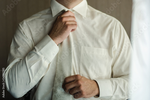 man in white shirt, man in white tie, groom tightens his tie, business style