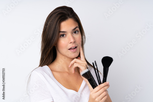 Teenager girl over isolated background holding makeup brush