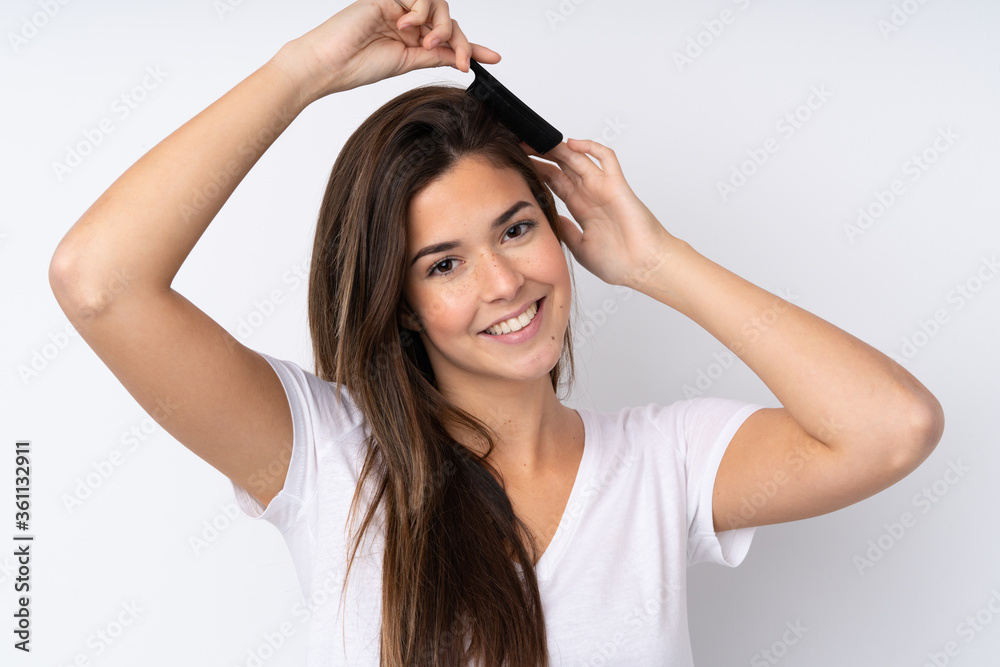 Teenager girl over isolated background with hair comb Teenager girl over isolated background with hair comb