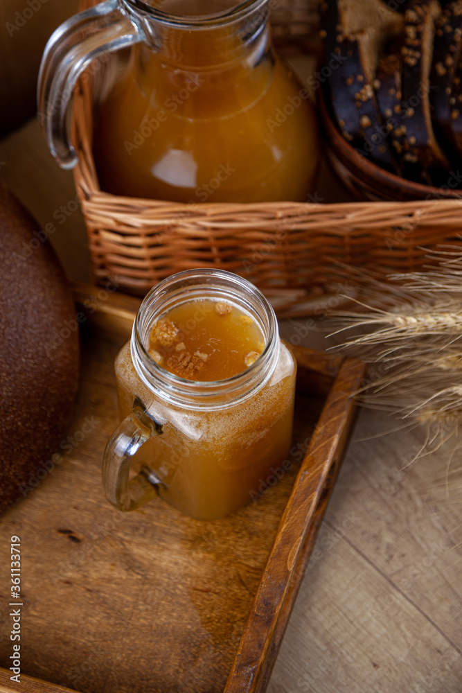 Homemade bread kvass. Summer carbonated soft drink. Glass and carafe on a wooden table. Black Overseas Rye Bread - Ingredients for a Drink. Copy space. Traditional cold rye drink Kvas in a jug. Homemade bread kvass. Summer carbonated soft drink. Glass and carafe on a wooden table. Black Overseas Rye Bread - Ingredients for a Drink. Copy space. Traditional cold rye drink Kvas in a jug.