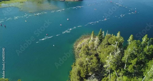 Air view of swimmers in Ironman triathlon competition crossing Lake Nahuel Huapi on a sunny summer day. Surrounded by mountains and vegetation photo