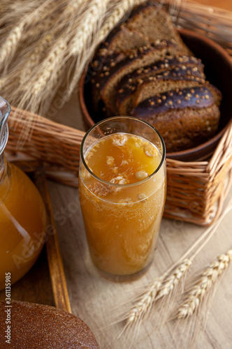 Homemade bread kvass. Summer carbonated soft drink. Glass and carafe on a wooden table. Black Overseas Rye Bread - Ingredients for a Drink. Copy space. Traditional cold rye drink Kvas in a jug.