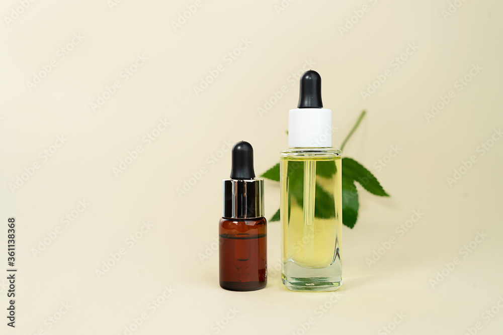 Herbal oil bottles aroma dropper on glass on pastel beige background. Herbal oil bottles aroma dropper on glass on pastel beige background.
