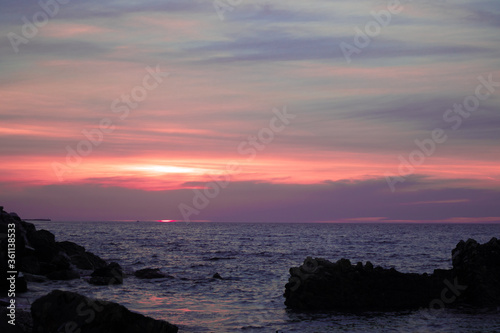 colorful yellow pink sunset on rocky beach with cloudy sky © KyriaKos Kinatidis