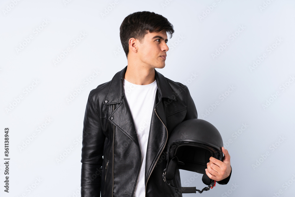 Man with a motorcycle helmet over isolated blue background looking side Man with a motorcycle helmet over isolated blue background looking side