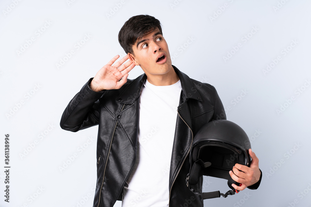 Man with a motorcycle helmet over isolated blue background listening something