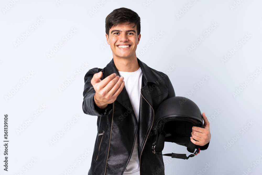 Man with a motorcycle helmet over isolated blue background inviting to come