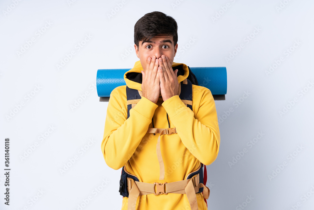 Young mountaineer man with a big backpack over isolated blue background with surprise facial expression Young mountaineer man with a big backpack over isolated blue background with surprise facial expression