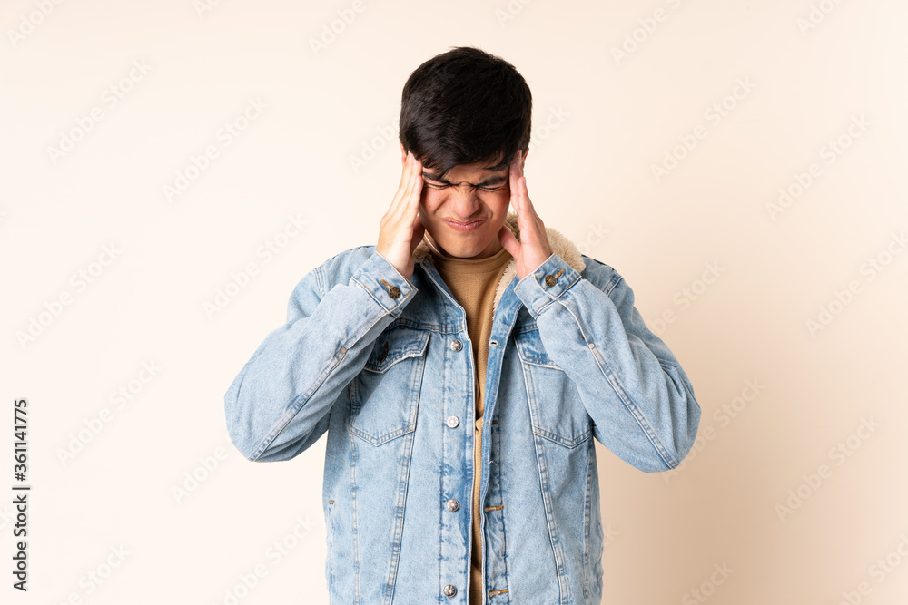Handsome man over isolated beige background with headache Handsome man over isolated beige background with headache