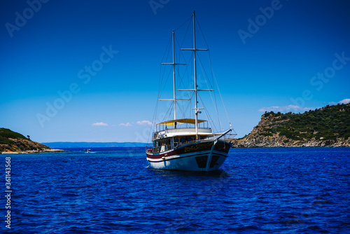 A two-masted yacht is anchored in the bay of the sea, ocean, lake. Rest on a yacht. Sailing. Vacation on a sea yacht. Mediterranean summer landscape. Seasickness.