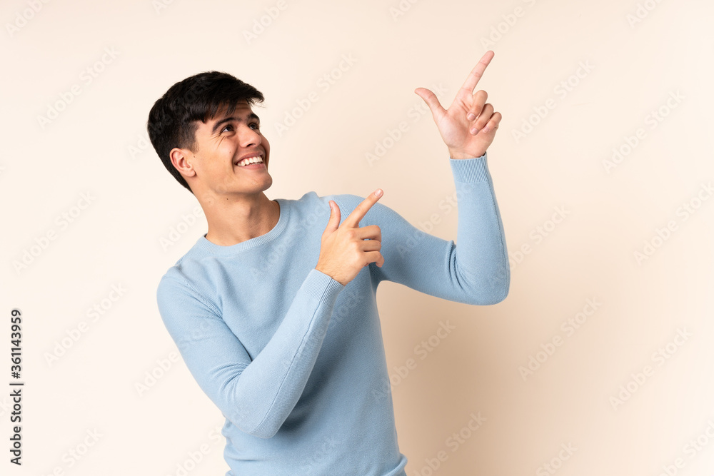 Handsome man over isolated beige background pointing with the index finger a great idea