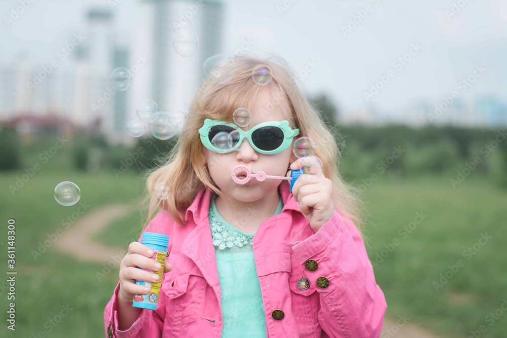 Cute child girl blowing soap bubble in summer park Cute child girl blowing soap bubble in summer park