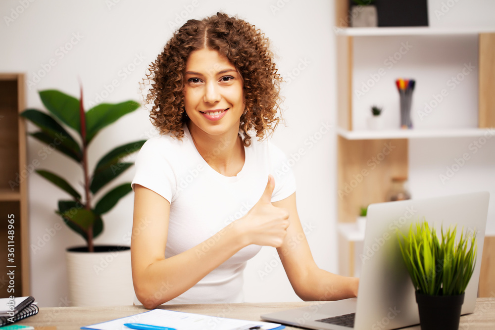 Beautiful business woman with a smile on her face working in the office on a laptop Beautiful business woman with a smile on her face working in the office on a laptop