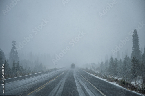 Car driving in heavy snow on highway in pine forest at Banff national park