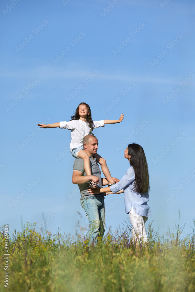 happy family father, mother and cute child girl having fun and playing in nature. daughter sits on father shoulders happy family father, mother and cute child girl having fun and playing in nature. daughter sits on father shoulders