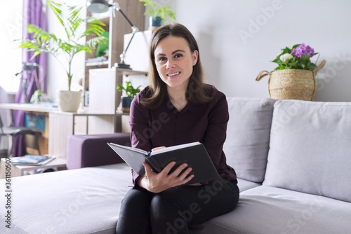 Portrait of young confident smiling female consultant, psychologist with business notebook photo
