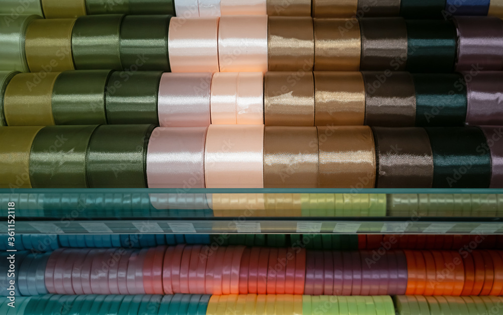 Shiny silk ribbons in rows on shelf in store. Homemade concept
