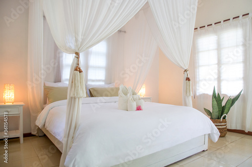 King size bed with mosquito net, bedroom interior in calm white colors, no people