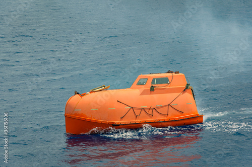 orange lifeboat moving in the sea © Vlad Ozo