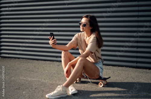 Young Woman With Longboard. Girl skater posing on longboard in sunny weather