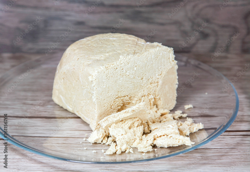 A large piece of peanut halva on a glass plate on a brown wooden background