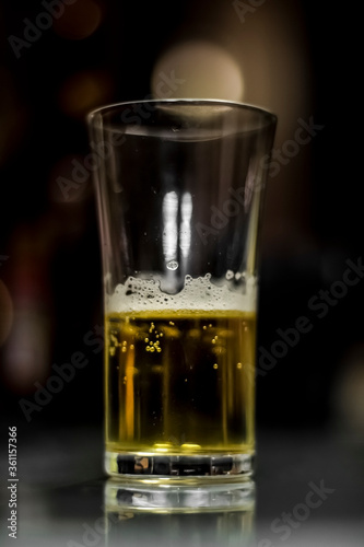 a glass of yellow colored alcoholic beverage / half empty