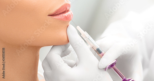 Woman having procedure lip augmentation. Syringe near womans mouth  injections for increase lips shape