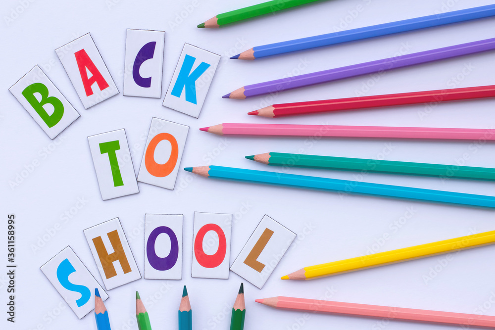 Back to school. Letters and colorful pencils on a white background. Flat lay. Education concept