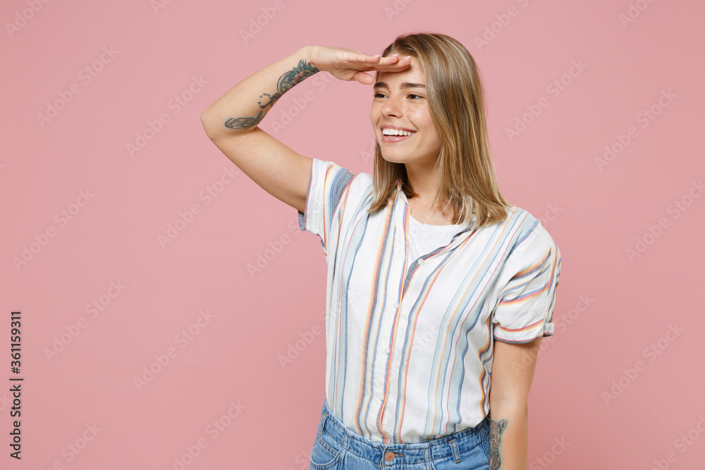 Smiling young blonde woman girl in casual striped shirt posing isolated on pastel pink wall background. People lifestyle concept. Mock up copy space. Hold hand at forehead looking far away distance. Smiling young blonde woman girl in casual striped shirt posing isolated on pastel pink wall background. People lifestyle concept. Mock up copy space. Hold hand at forehead looking far away distance.