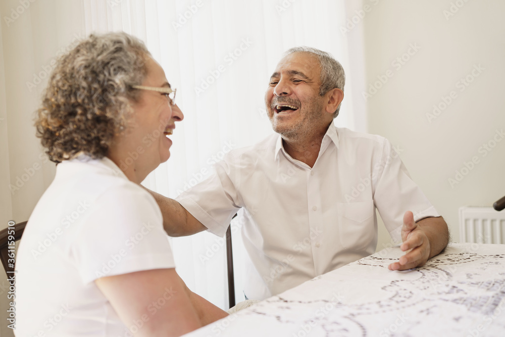 Happy elderly couple, quarantined because of covid-19, sitting together at home, chatting and laughing. Happy elderly couple, quarantined because of covid-19, sitting together at home, chatting and laughing.