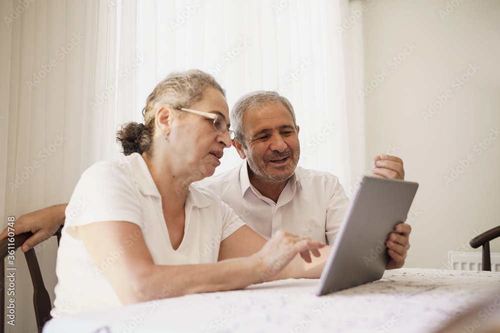 Happy senior couple wave having video call on laptop talking with relatives, smiling aged husband and wife sit on couch at home communicating via online using computer. Elderly and technology concept Happy senior couple wave having video call on laptop talking with relatives, smiling aged husband and wife sit on couch at home communicating via online using computer. Elderly and technology concept