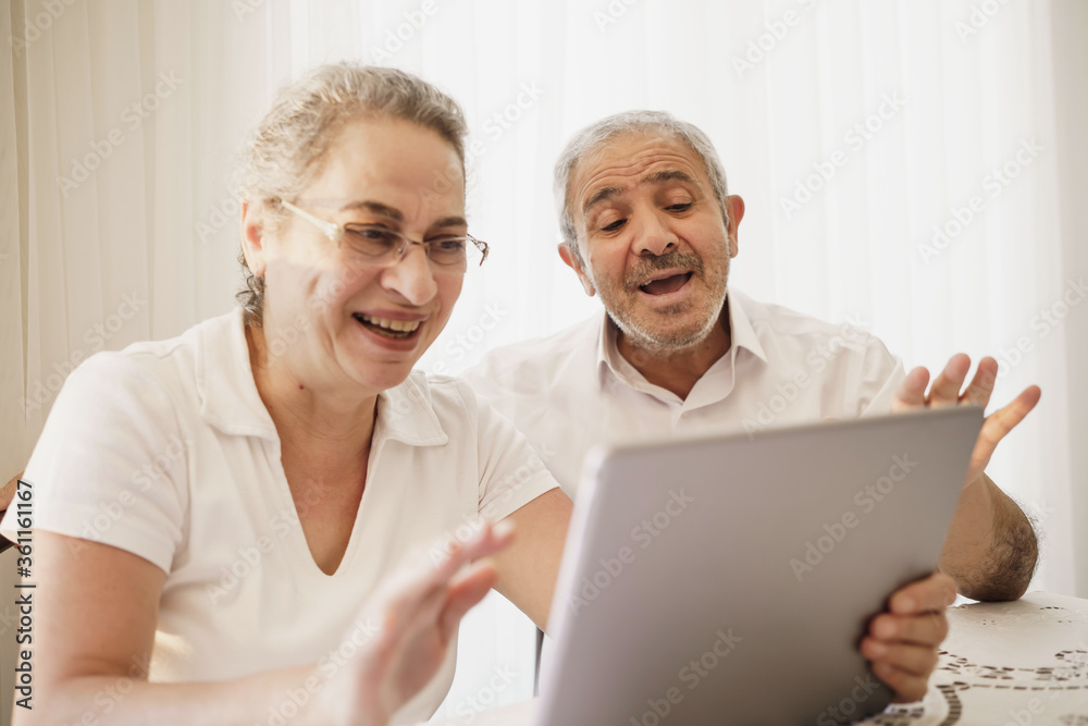 The elderly couple trying to use the tablet show each other something on the screen. old couple is trying to talk to their grandchildren. elders enjoying with benefits of technology The elderly couple trying to use the tablet show each other something on the screen. old couple is trying to talk to their grandchildren. elders enjoying with benefits of technology