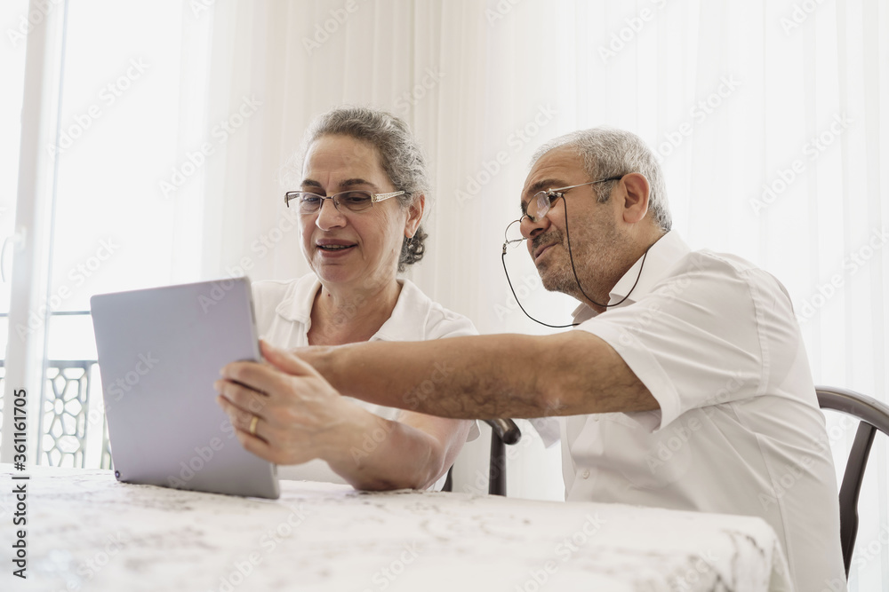 Obraz premium The elderly couple trying to use the tablet show each other something on the screen. old couple is trying to talk to their grandchildren. elders enjoying with benefits of technology