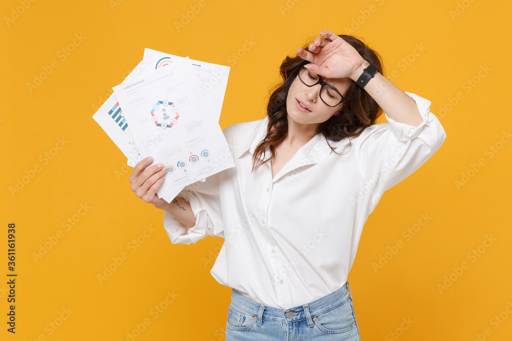 Exhausted young brunette business woman in white shirt glasses isolated on yellow background. Achievement career wealth business concept. Mock up copy space. Hold papers document, put hand on head. Exhausted young brunette business woman in white shirt glasses isolated on yellow background. Achievement career wealth business concept. Mock up copy space. Hold papers document, put hand on head.