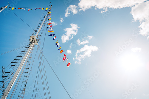 Sailboat mast without veil with nautical signs flags, space for copy text.