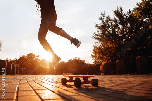 Obraz na płótnie silhouette of a jumping girl on a skateboard in the setting sun in the park w salonie
