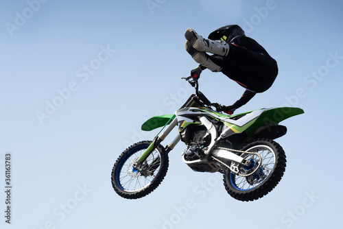 man in a helmet performs a stunt in the air on a motorcycle