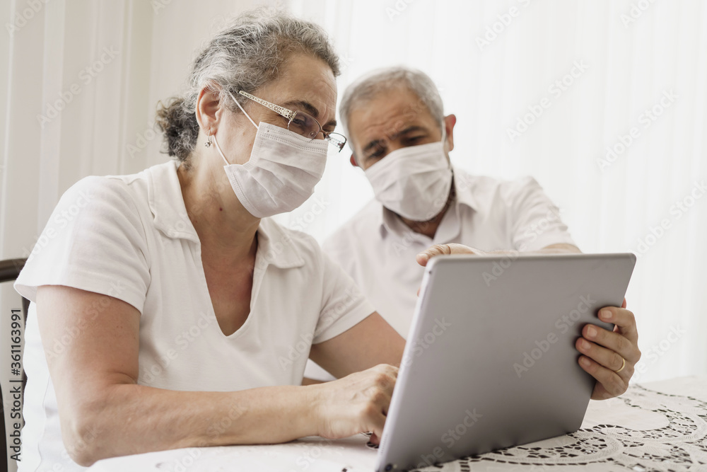 The elderly couple trying to use the tablet show each other something on the screen. old couple is trying to talk to their grandchildren. old couple is trying to talk to their children.