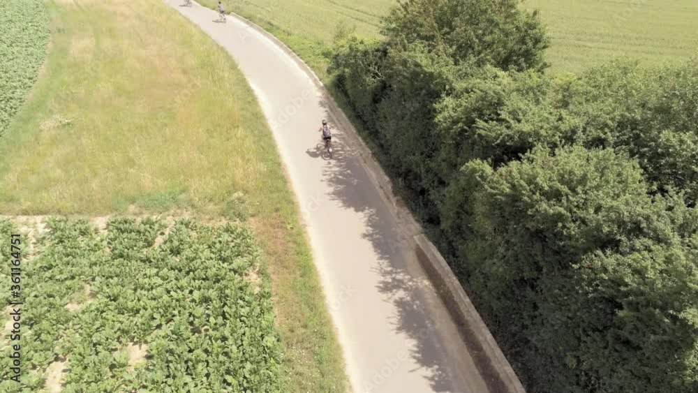 A single rider quickly catches up to a larger group of bicyclists, drought stricken fields, aerial A single rider quickly catches up to a larger group of bicyclists, drought stricken fields, aerial