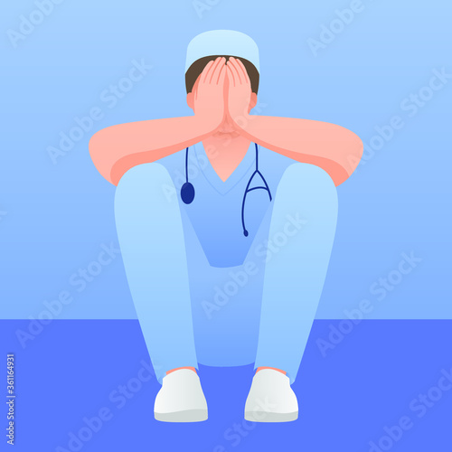 Exhausted doctor sitting on the floor in corridor at hospital. COVID-19, Coronavirus pandemic. Tired medical worker crying.