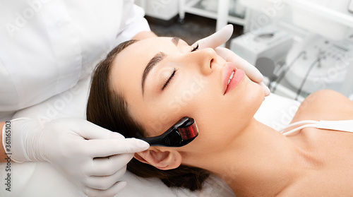 Beautician doing skin treatment using a microneedle derma roller. Woman getting procedure skincare, with mezzo skin roller photo