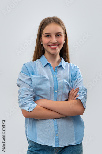Studio shot of young smiling girl teenager with cross arms, isolated