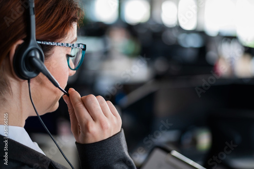 Rear view of a female helpdesk operator. An office manager with a headset answers customer calls. Unrecognizable woman in glasses works as a secretary. Employee call center.
