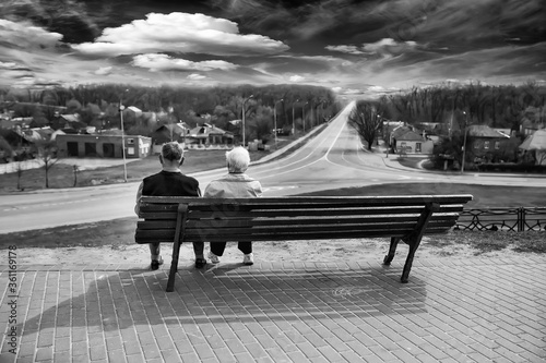 Older people sit on a bench and look into the distance