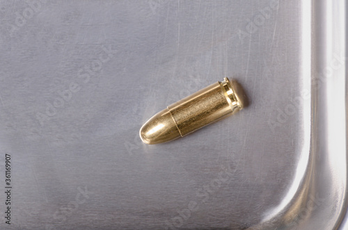 a brass full metal jacket bullet rest on a stainless steel background