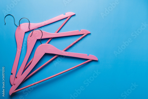 Pink empty wooden clothes hangers on pastel blue background.