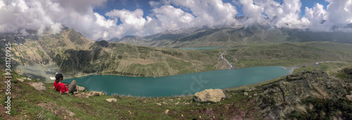 Panoramic view lake and mountains. Hiker enjoying view of landscape. © Malik Haris