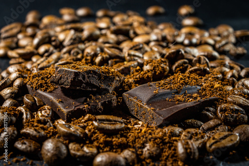 Pieces of dark chocolate among coffee beans. Close-up with a blurred background.